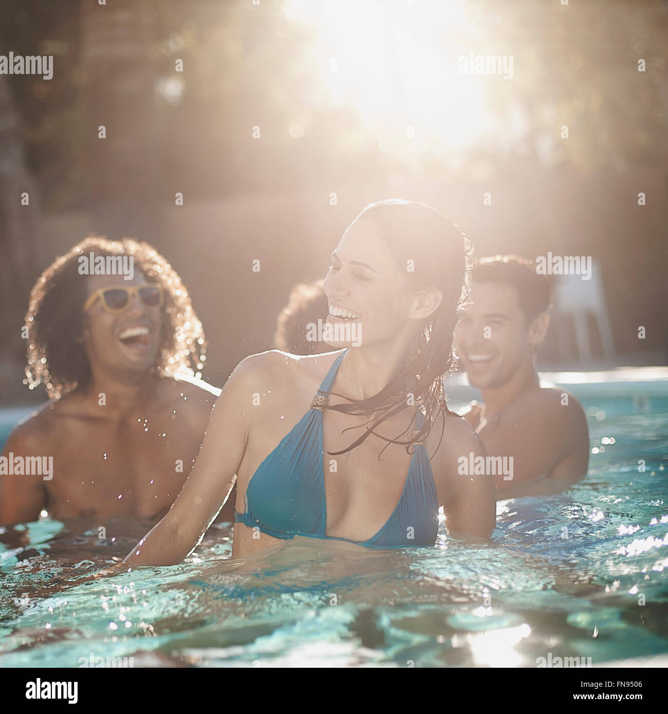 Eine Gruppe von jungen Männern und Frauen im Schwimmbad am Ende eines heißen Tages. Stockfoto