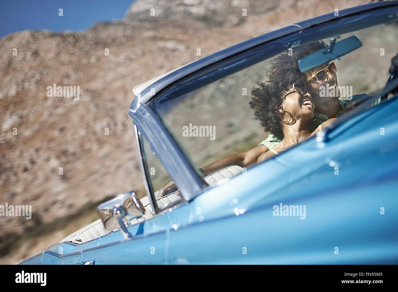 Ein junges Paar, Mann und Frau in einem blassen Blau Cabrio auf offener Straße Stockfoto