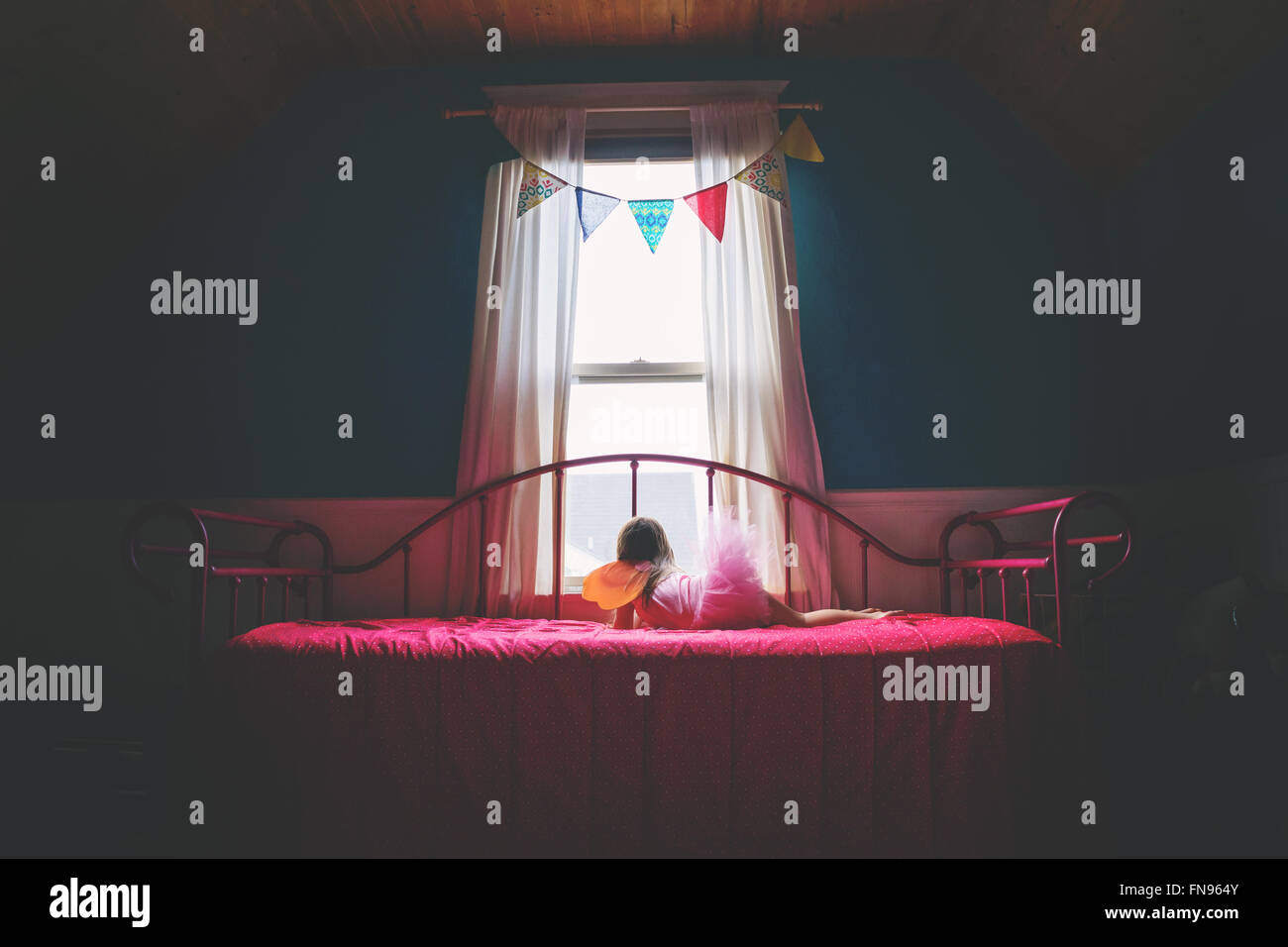 Mädchen in einem Feuer Kostüm liegt auf dem Bett und schaut aus dem Fenster Stockfoto