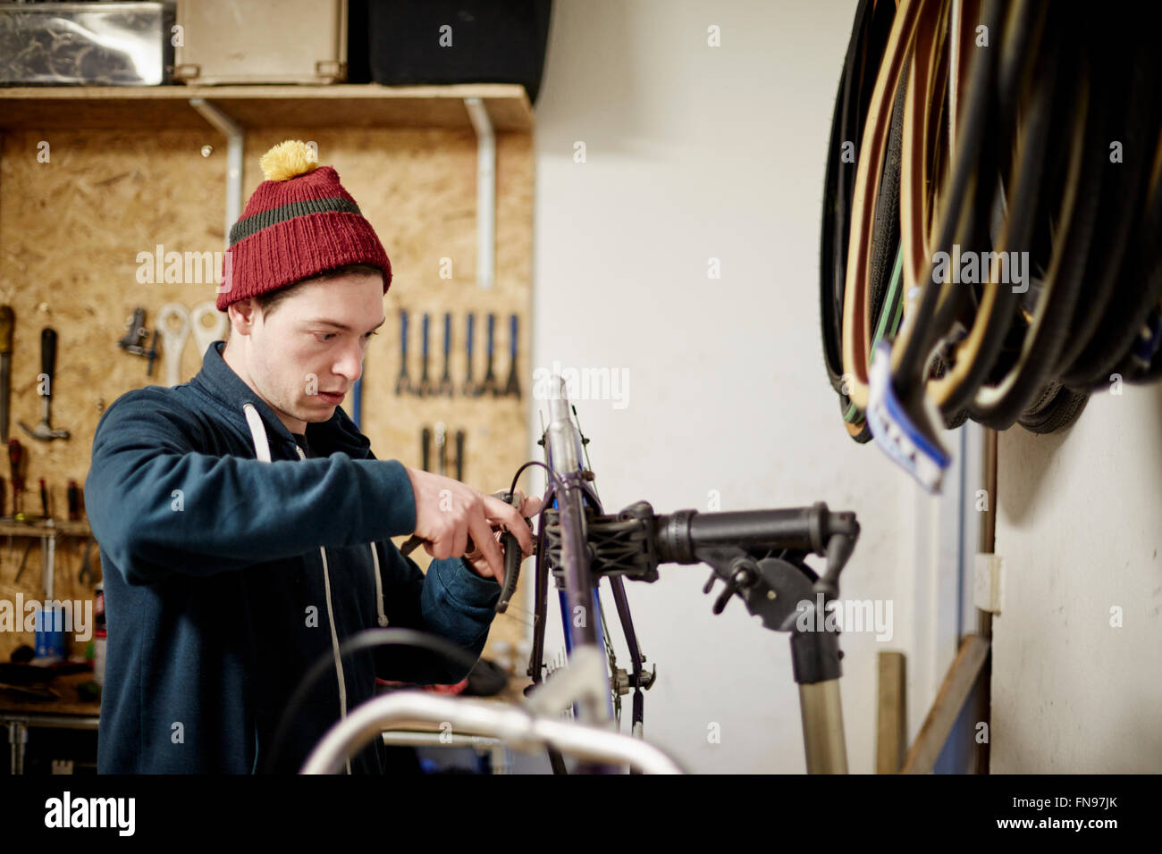 Ein junger Mann arbeitet in einem Zyklus-Shop, ein Fahrrad zu reparieren. Stockfoto