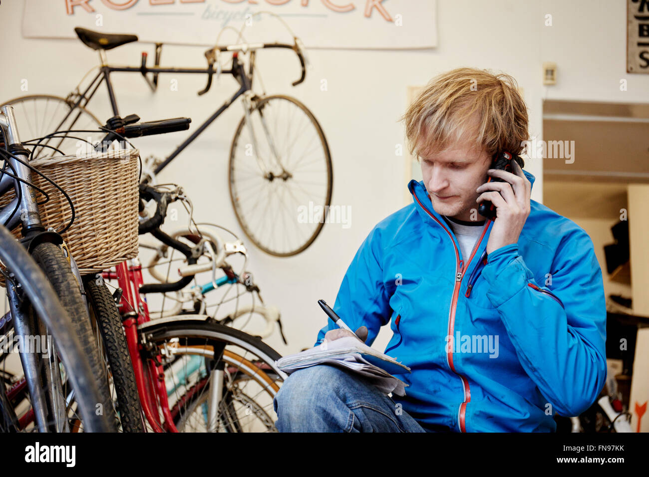 Ein junger Mann mit seinem Smartphone in einem Zyklus laden, einen Anruf tätigen. Stockfoto