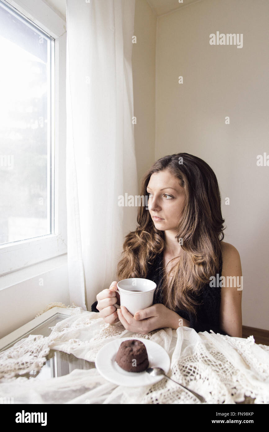 Junge Frau sitzt mit einer Tasse Tee und Schokolade dessert Stockfoto