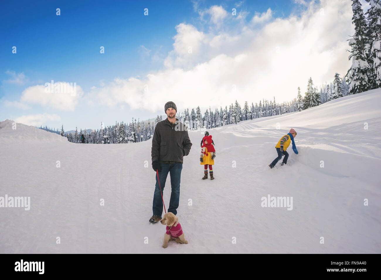 Vater mit drei Kindern und einem golden Retriever Welpe Hund im Schnee Stockfoto