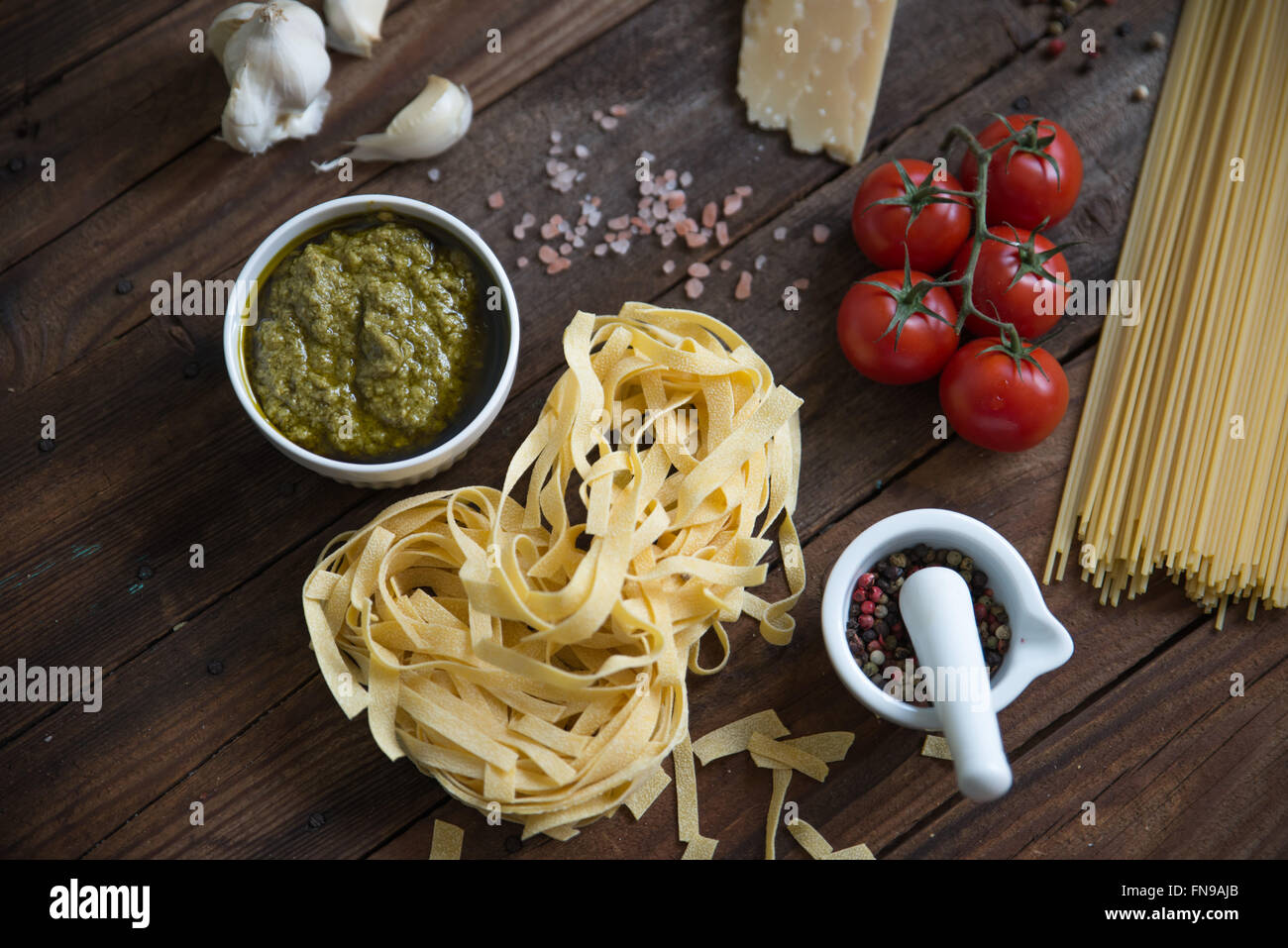 Pasta, Pesto, Knoblauch, Tomaten und Parmesan auf Tisch Stockfoto