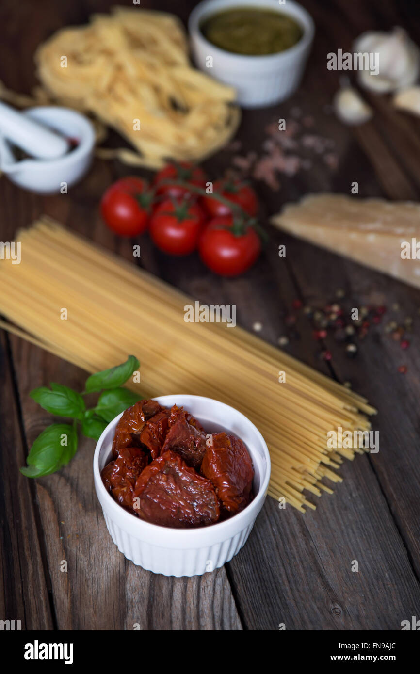 Pasta, Pesto, Knoblauch, Tomaten und Parmesan auf Tisch Stockfoto