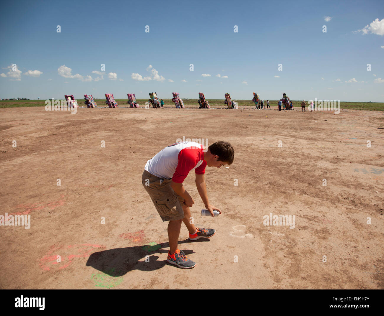 Ein Teenager Spritzlackierung Boden auf Cadillac Ranch in Amarillo, Texas am 13. Juli 2015. Stockfoto