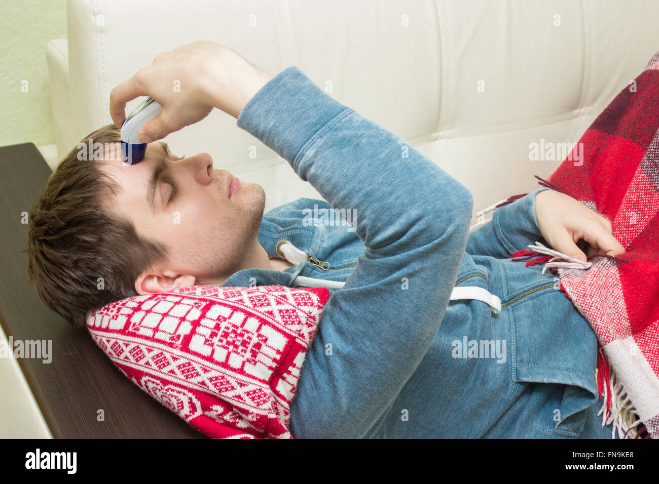 Kranker Mann Temperatur überprüfen, auf dem Sofa liegend Stockfoto