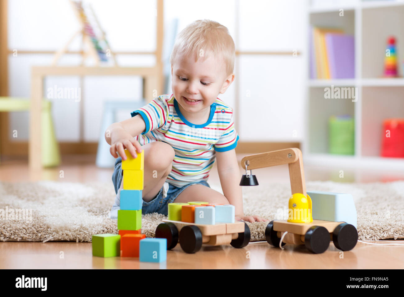 Kind Junge ist glücklich, spielen Spielzeug Bausteine und Verladewagen Stockfoto
