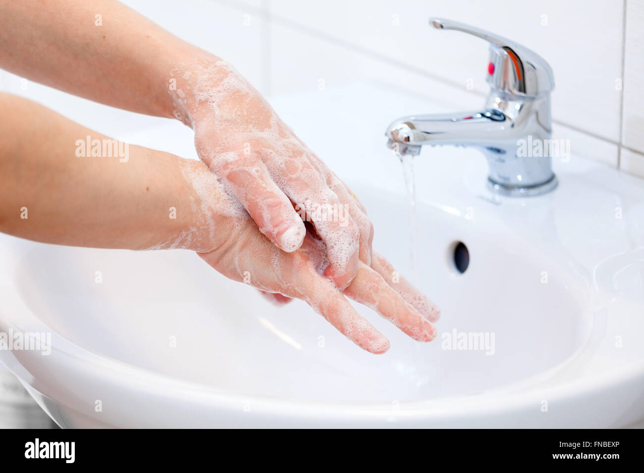 Waschen der Hände mit Seife unter fließendem Wasser. Hygiene und Reinigung der Hände. Stockfoto