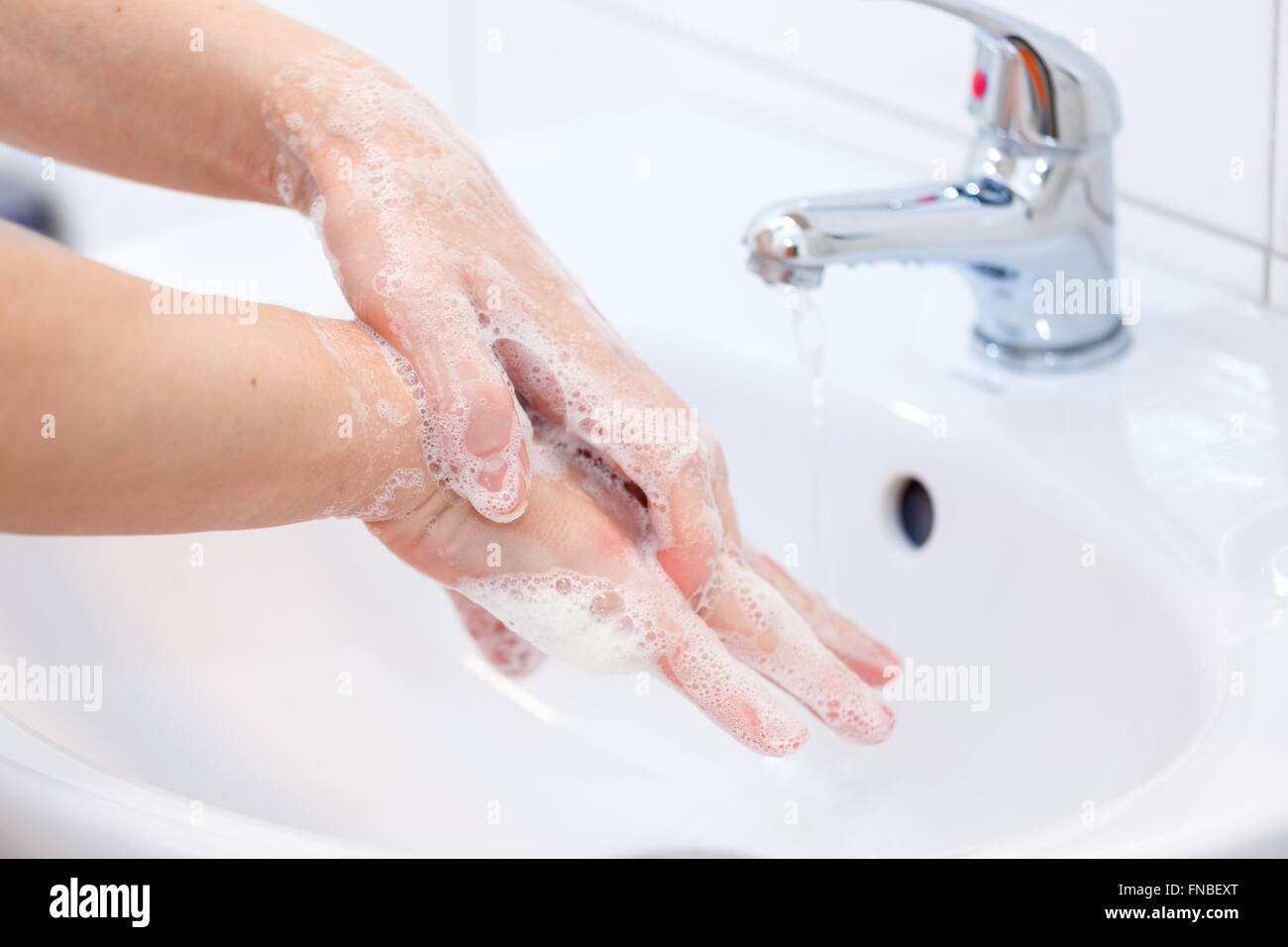 Waschen der Hände mit Seife unter fließendem Wasser. Hygiene und Reinigung der Hände Stockfoto