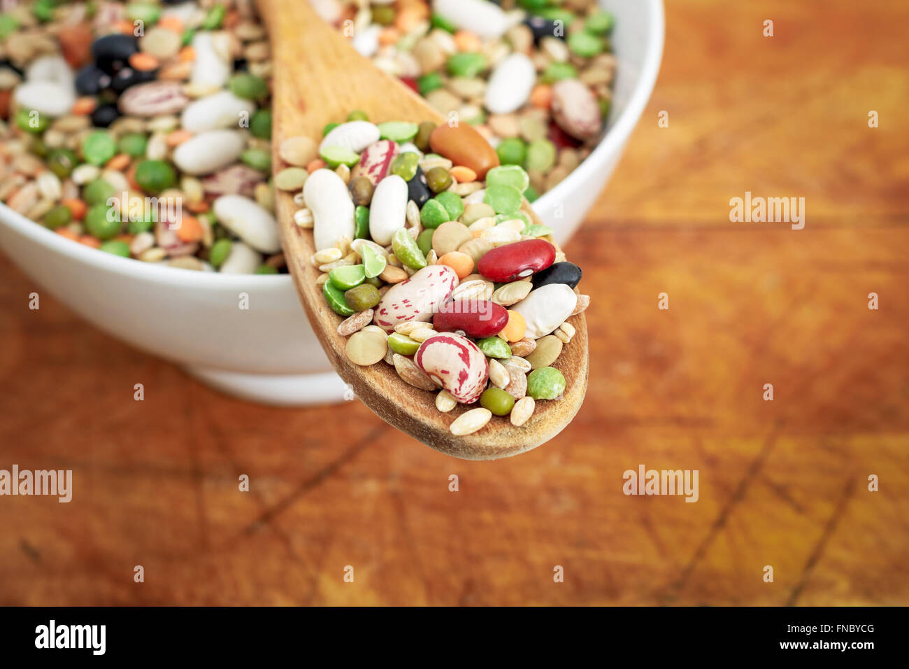 Gemischte getrocknete Hülsenfrüchte und Getreide in Holzlöffel auf hölzernen Hintergrund. Textfreiraum Stockfoto
