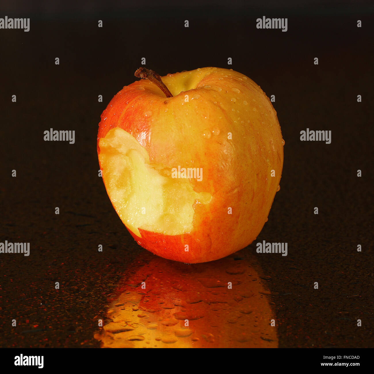 Apfel vor dunklem Hintergrund beißen Stockfoto