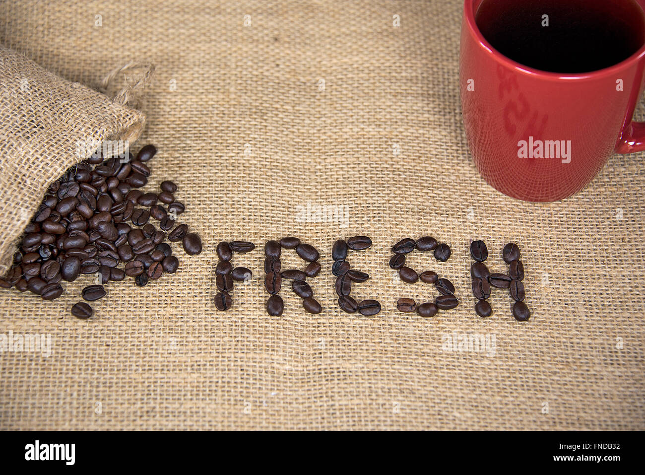 Frische Kaffeebohnen auf Sackleinen mit roten Becher. Stockfoto