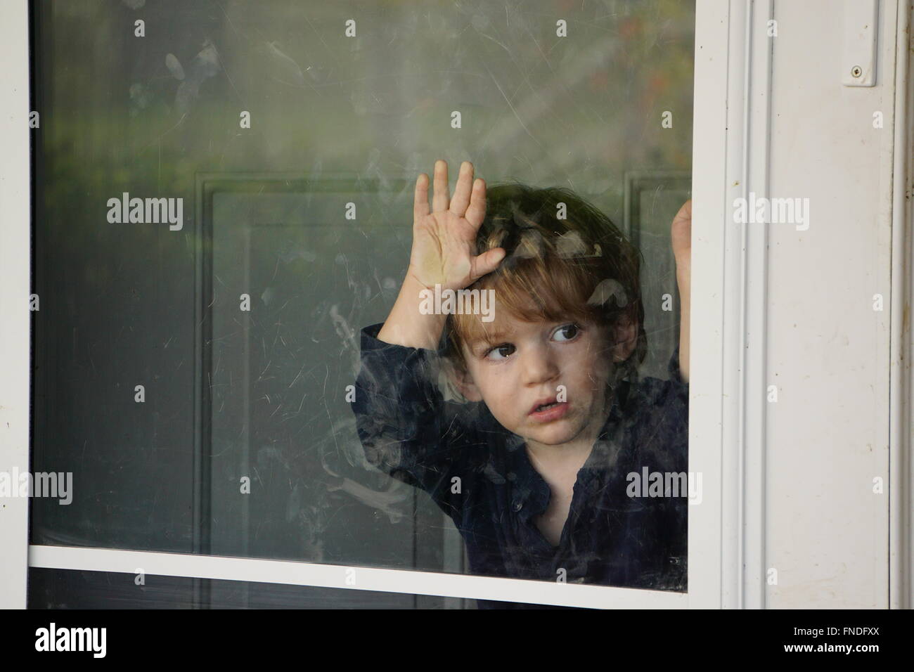 Junge nach draußen durch eine Glastür Stockfoto