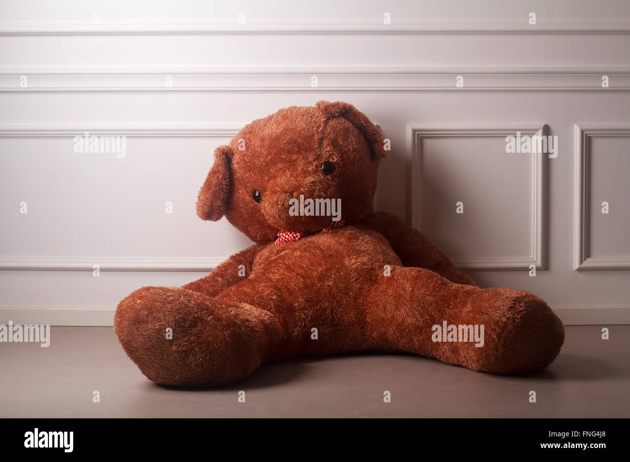 Dicken Gummischwanz tragen mit einem gepunkteten Schleife stehen auf dem Boden gegen die weiße Wand von einem leeren Raum Stockfoto