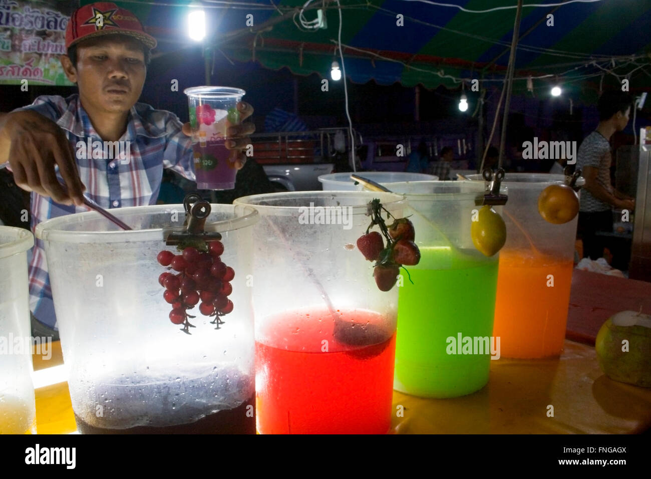 Ein Mann verkauft süße Getränke aus Orangen, Zitronen, Erdbeeren und Trauben an einer Straßenecke Messe in Kampong Cham, Kambodscha hergestellt. Stockfoto