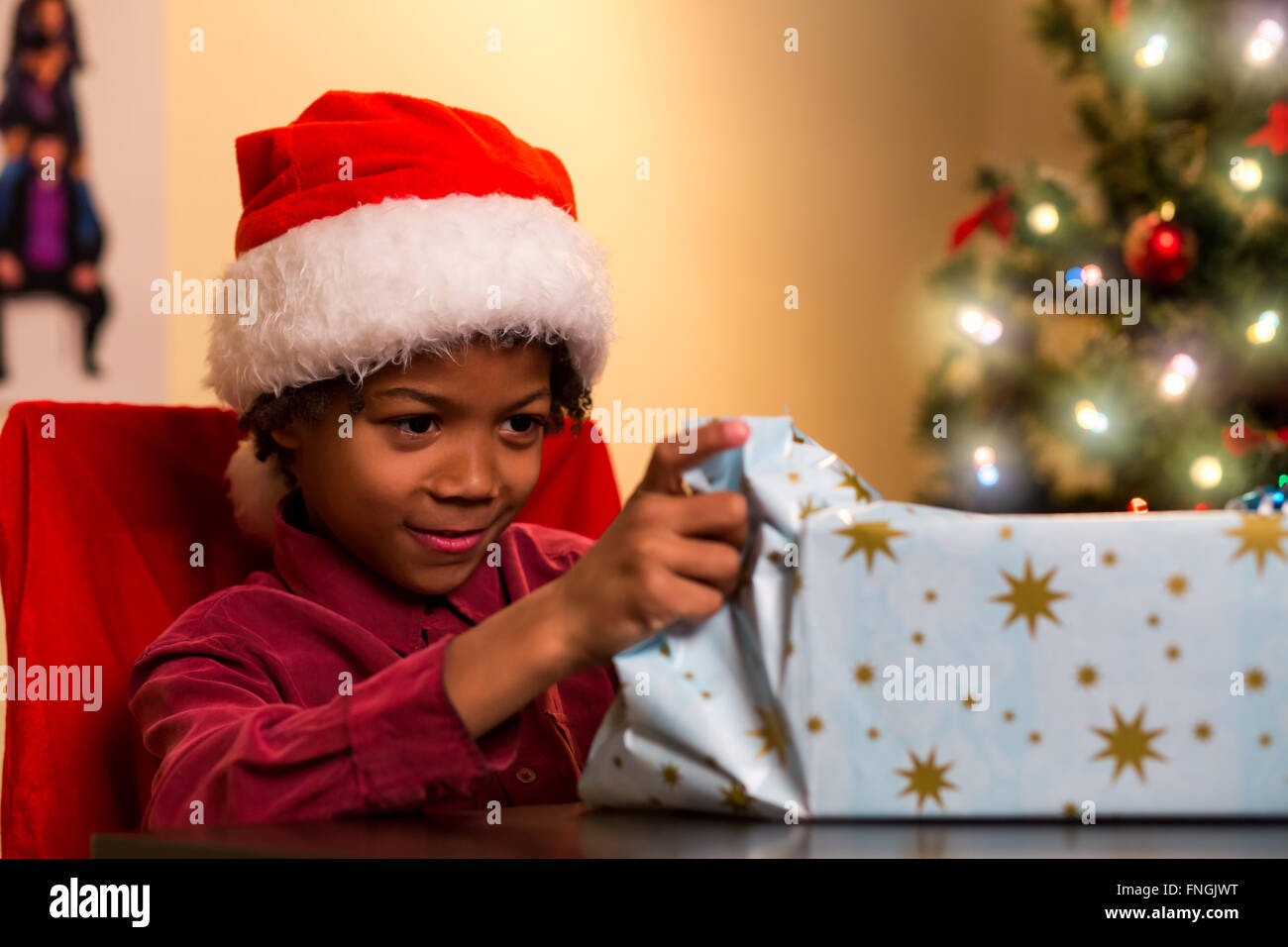 Schwarzer Junge Weihnachtsgeschenk zu öffnen. Stockfoto