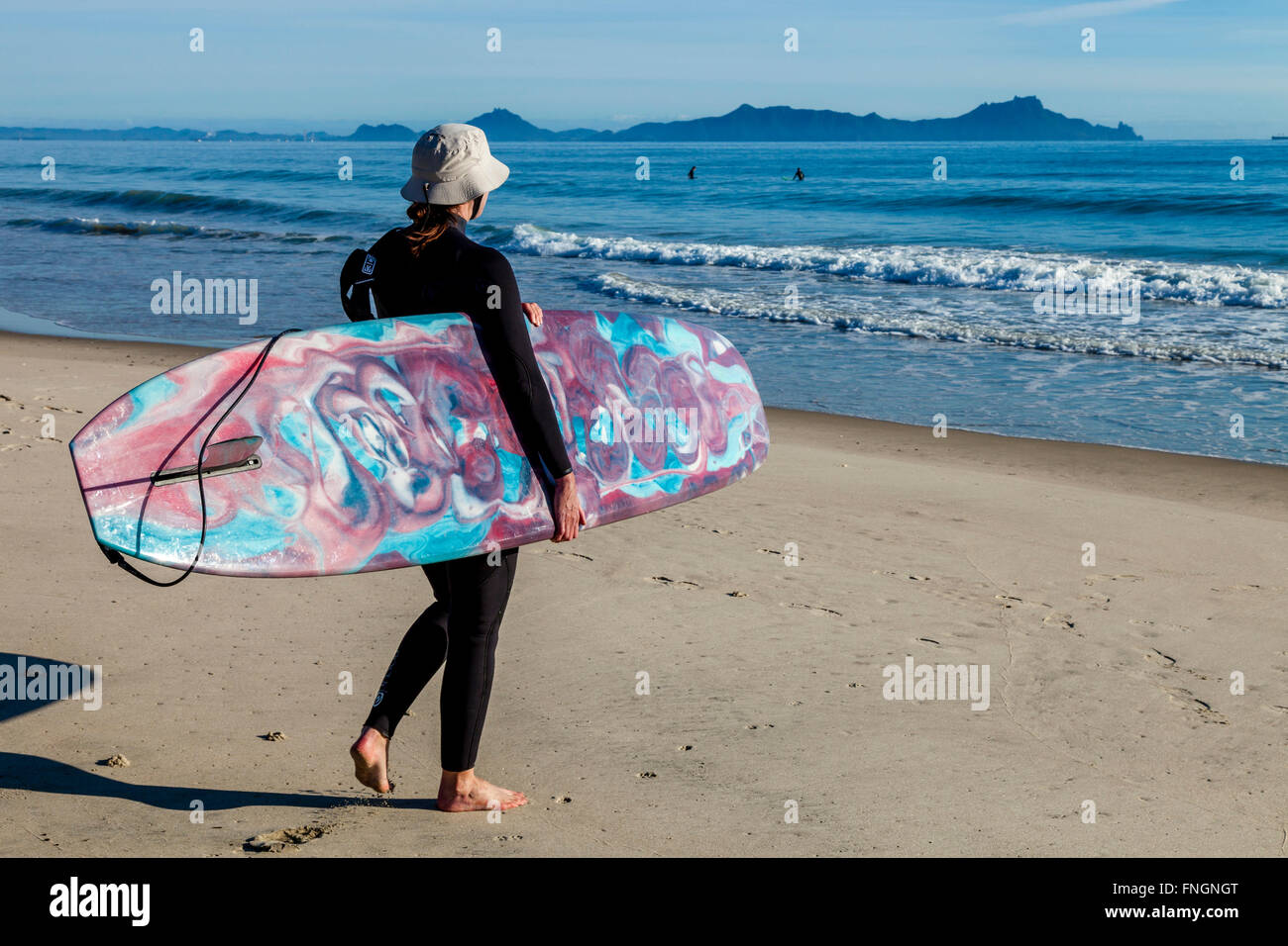 Eine Frau geht surfen, Waipu Cove, Waipu, Northland, Neuseeland Stockfoto