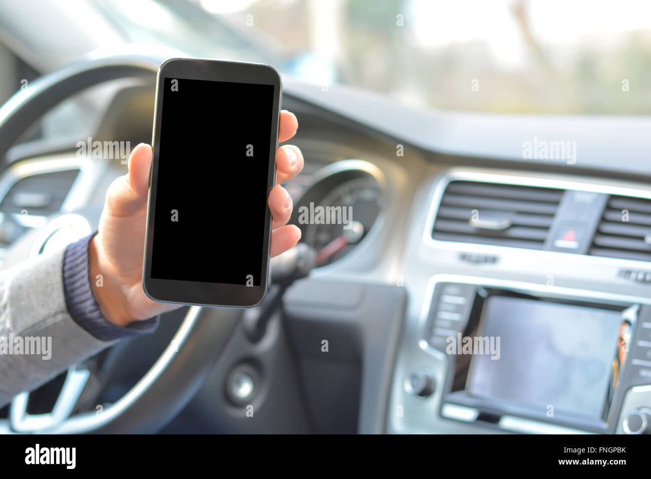 Smartphone halten von Mann in einem Auto während der Fahrt Stockfoto