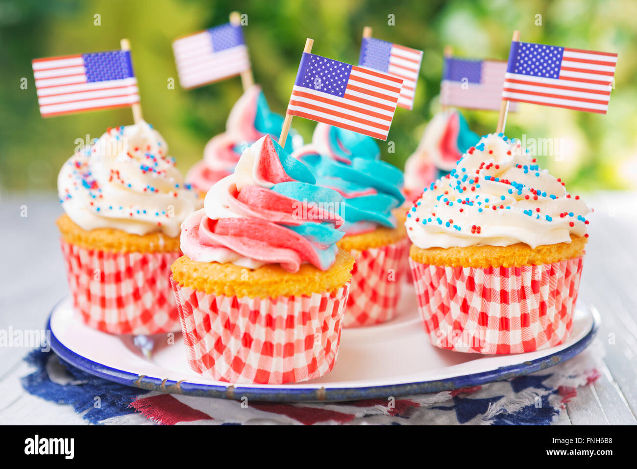 Rot-weiss-blaue Cupcakes mit amerikanischen Flaggen auf einen Tisch im Freien. Stockfoto