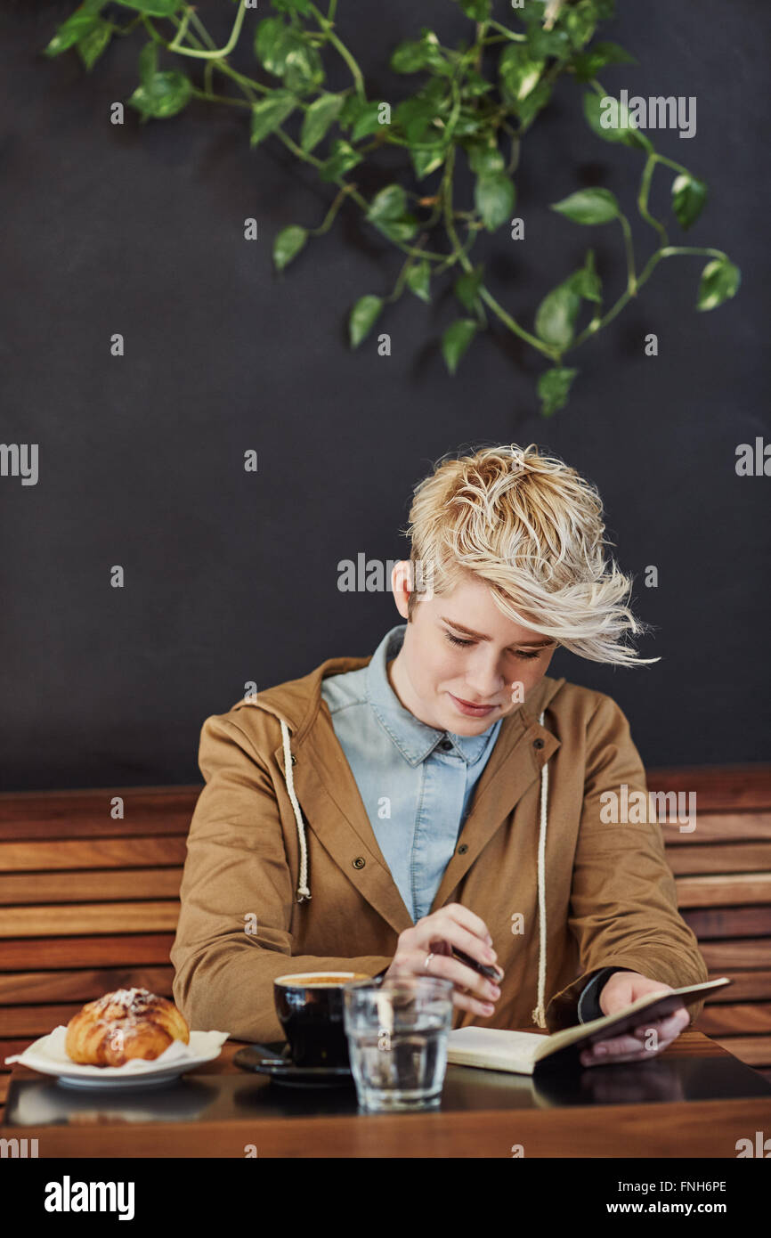 Junge Frau im Café schreiben in Notebook mit dunklem Hintergrund Stockfoto