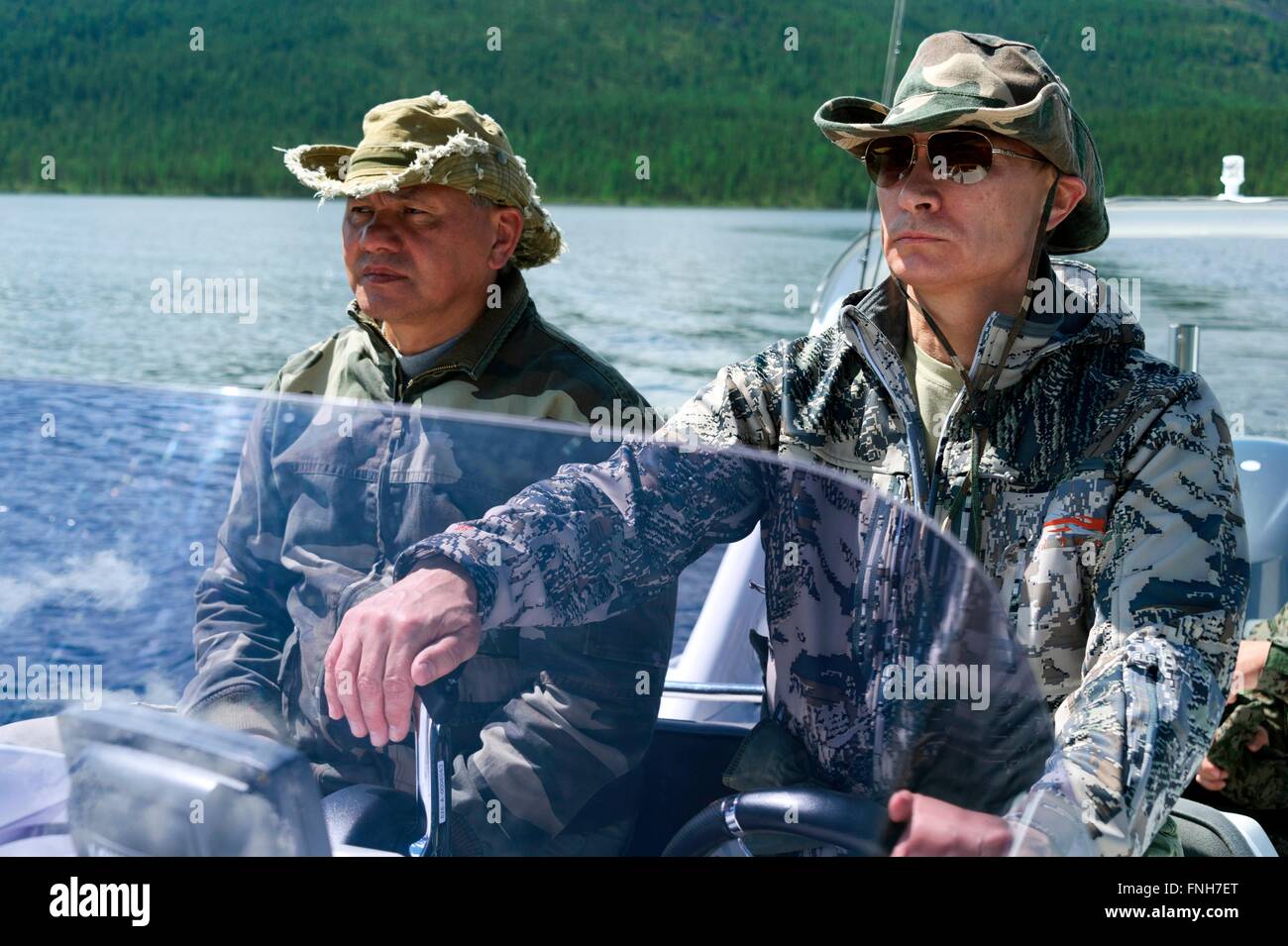 Der russische Präsident Vladimir Putin neben Verteidigungsminister Sergei Shoigu Pilot ein Motorboot während eines kurzen Urlaubs 20. Juli 2013 in der sibirischen Tuwa-Region, Russland Stockfoto