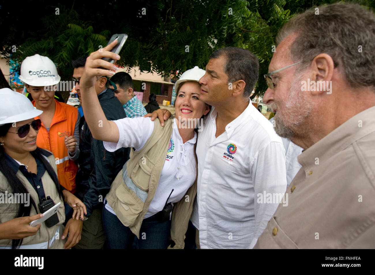 Peter Greenberg schaut zu, wie Präsident Correa für das Selfie mit einer Frau auf einer Baustelle in Manta, Ecuador stellt, während der Dreharbeiten zu Reisedokumentation Ecuador: The Royal Tour. Stockfoto