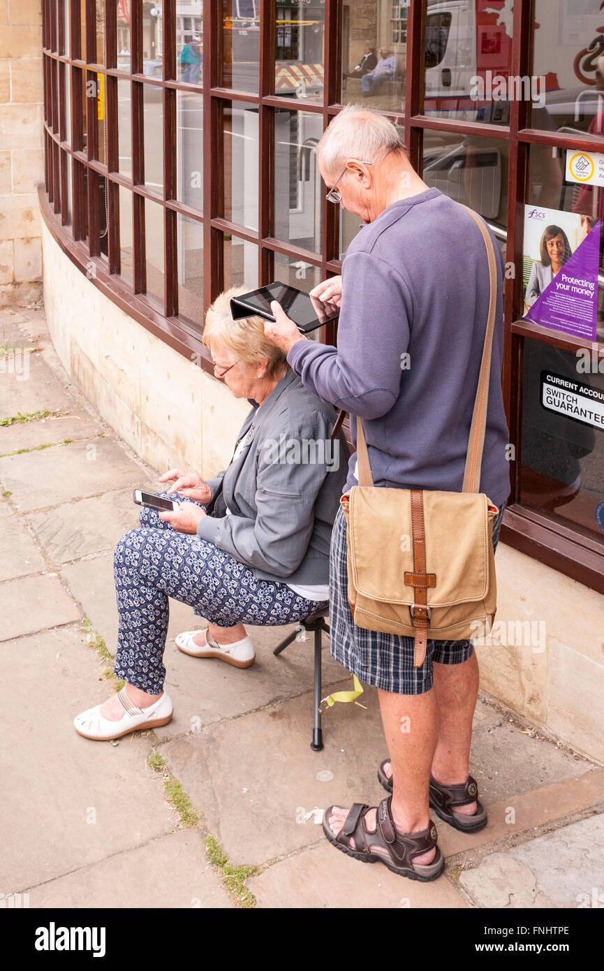Ein Elderley Ehepaar versunken in ihre Tablet und Handy-Gadgets im Vereinigten Königreich Stockfoto