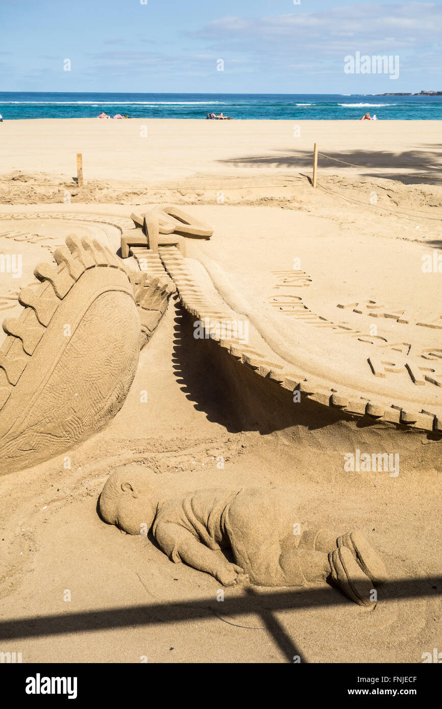 Las Palmas, Gran Canaria, Kanarische Inseln, Spanien, 15. März 2016. Sand Skulptur von Etual Ojeda am Stadtstrand in Las Palmas Hervorhebung der politischen und finanziellen Unterschiede zwischen Armen und reichen. Die Abbildungen zeigen einen übergewichtigen Mann Sonnenbaden, eine Zigarre rauchend und halten eine Handvoll Geld; während auf der rechten Seite der seine Füße ein junger Flüchtling junge Gesicht am Strand hinlegt (zeigt Aylan Kurdi, der drei Jahre alten syrischen junge, dessen Bild der Welt schockiert, als sein leblose Körper Gesicht nach unten auf einen türkischen Strand gefunden wurde. Bildnachweis: Alan Dawson News/Alamy Live-Nachrichten Stockfoto