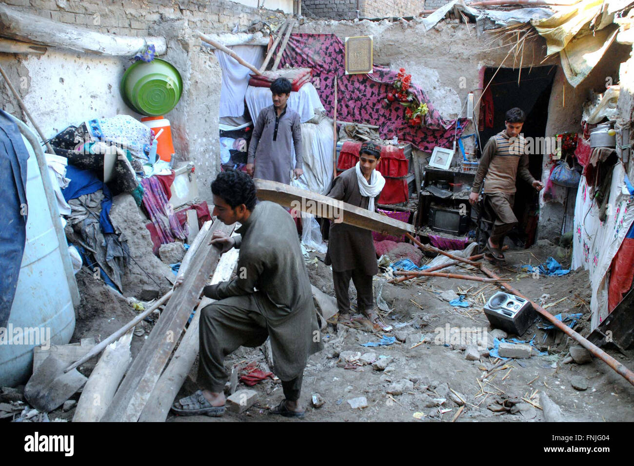 Die Leute schauen beschädigte Sachen, die zerstört wurde, als das Dach ihres Hauses während starker Regenguss nach Dach einstürzen Vorfall im Saeedabad Bereich in Peshawar auf Dienstag, 15. März 2016 zusammengebrochen war. Stockfoto