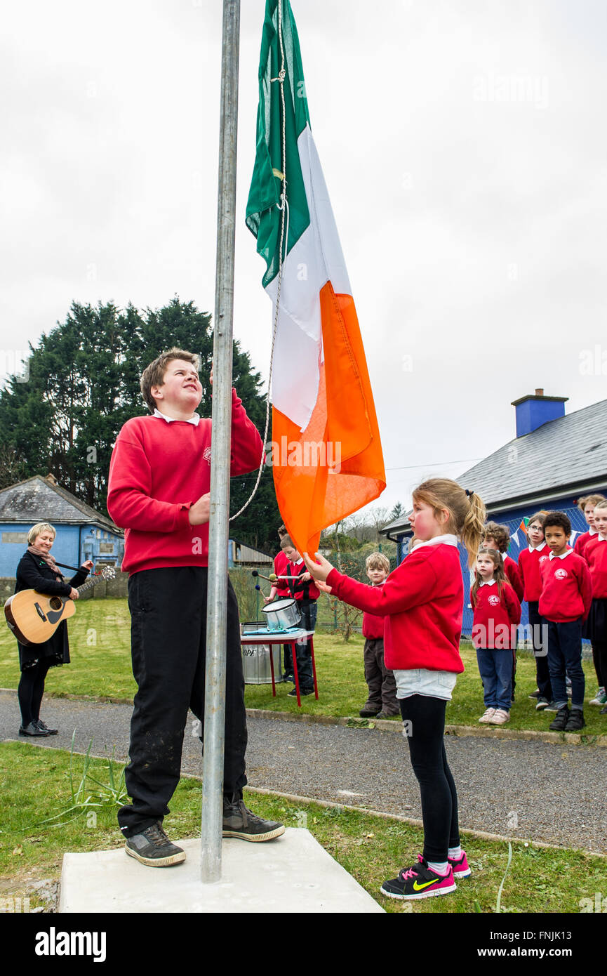 Durrus, Irland. 15. März 2016. Schülerinnen und Schüler Stephen Dukelow und Anna Walker erhöhen die irische Trikolore während andere Schüler auf St James National School, Durrus, am Tag der Verkündigung zu suchen zur Erinnerung an die Ereignisse des Jahres 1916 stattfand. Bildnachweis: Andy Gibson/Alamy Live-Nachrichten. Stockfoto