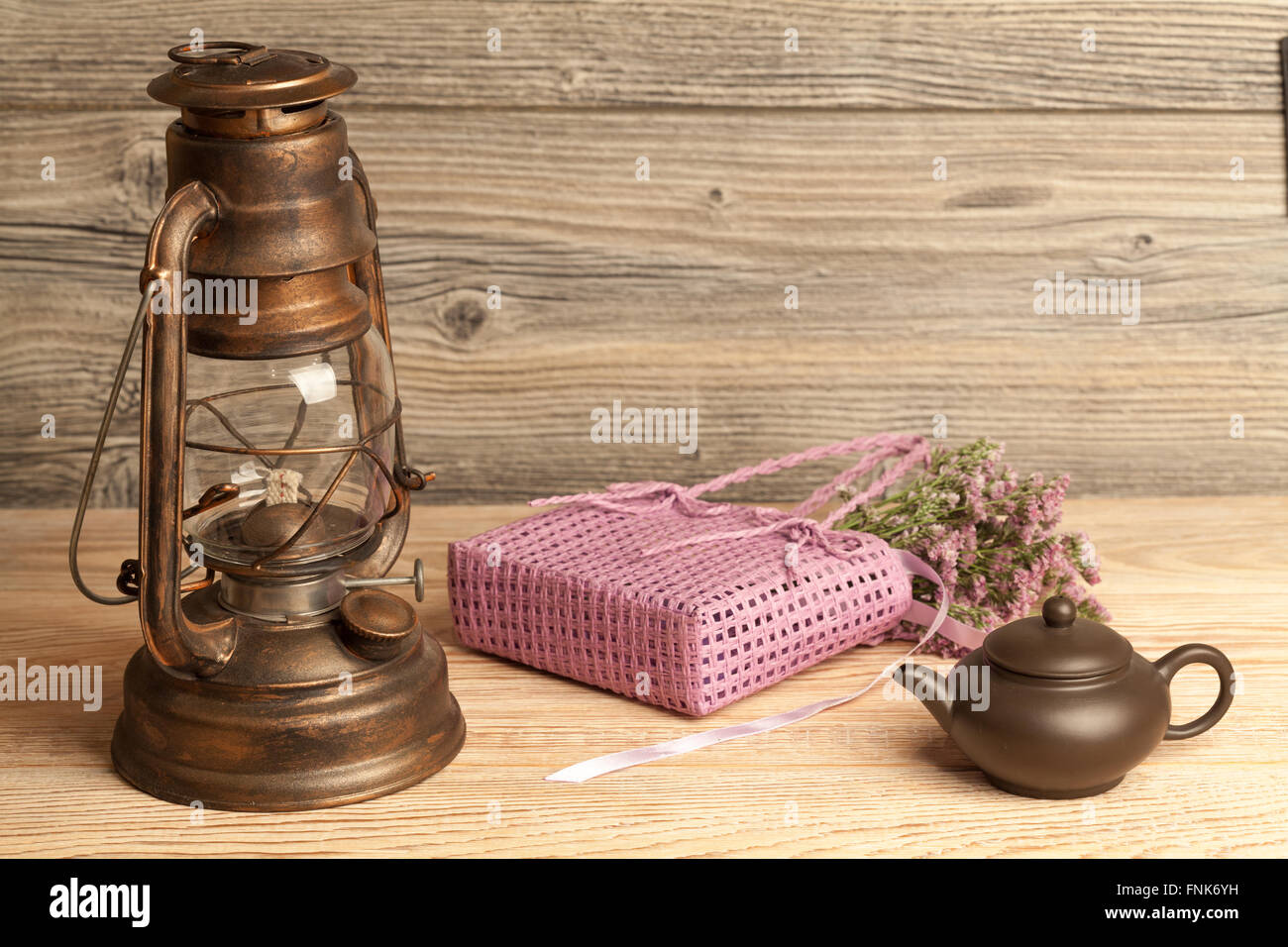 Petroleumlampe, Teekanne, Blumen und Tasche auf hölzernen Hintergrund Stockfoto