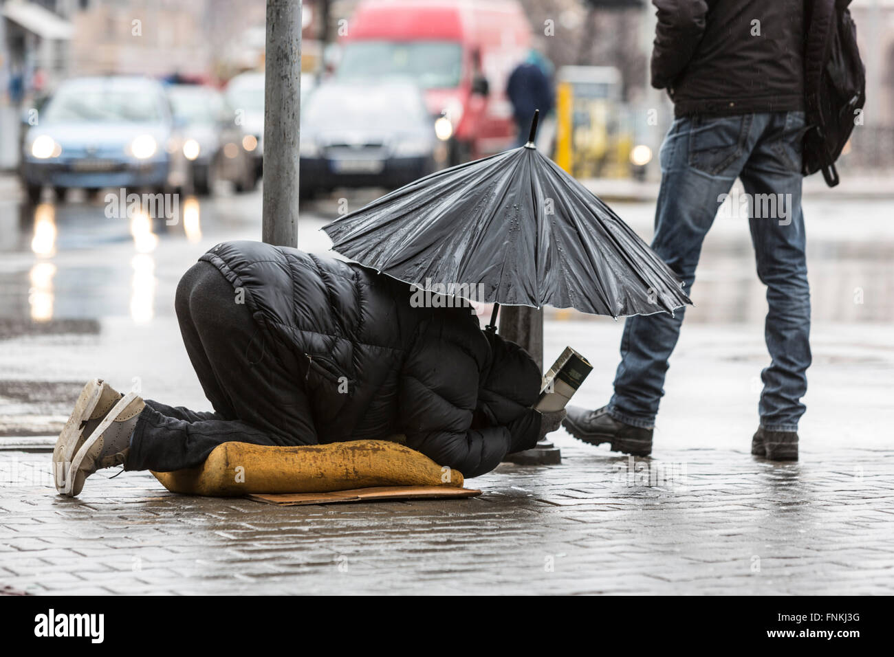 Mit Schirm im Regen in der Nähe von einem Gehweg an einer Hauptstraße in Sofia ist Obdachlose Bettler betteln. Bulgarien ist eines der ärmsten co Stockfoto