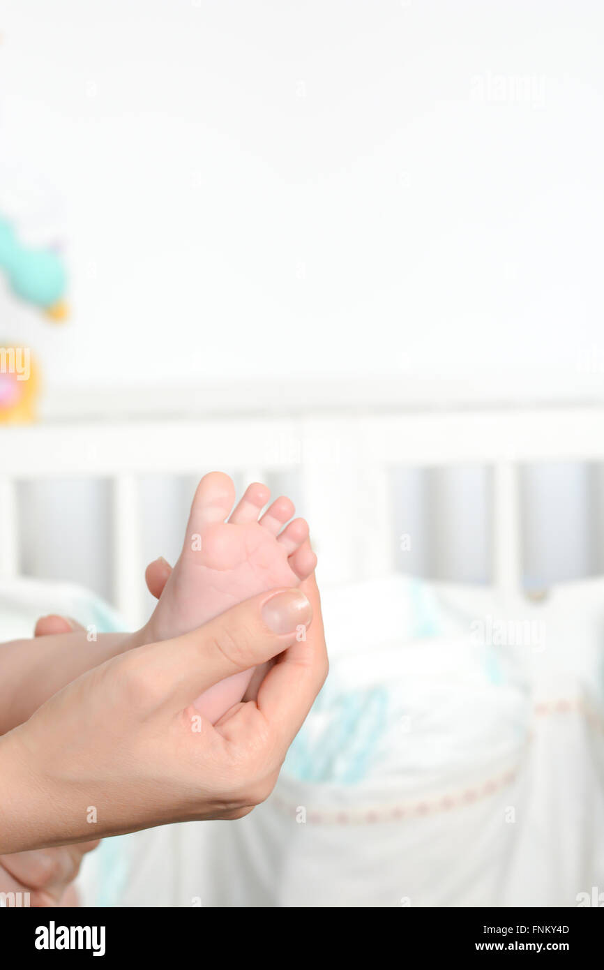 Junge Mutter Neugeborenes Fuß in ihre Handflächen halten Stockfoto