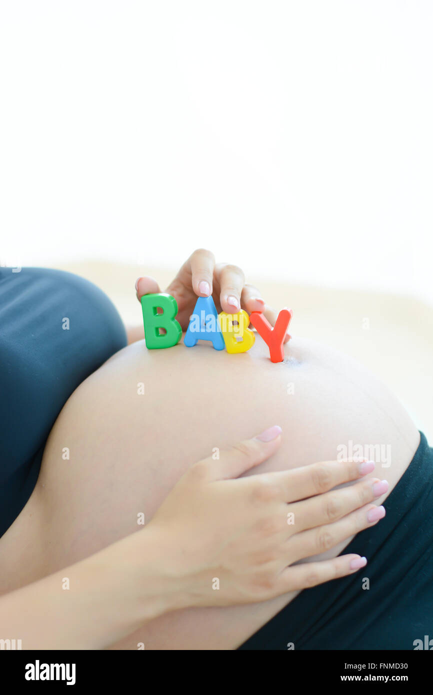 Junge werdende Mutter mit Baby auf ihren schwangeren Bauch Rechtschreibung Buchstaben-Blöcke Stockfoto