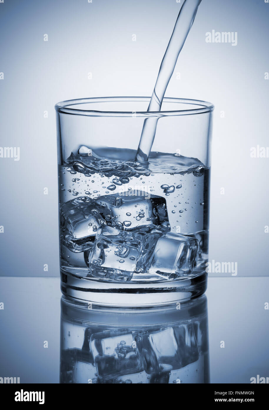 Wasser in Glas mit Eiswürfeln gießen Stockfoto