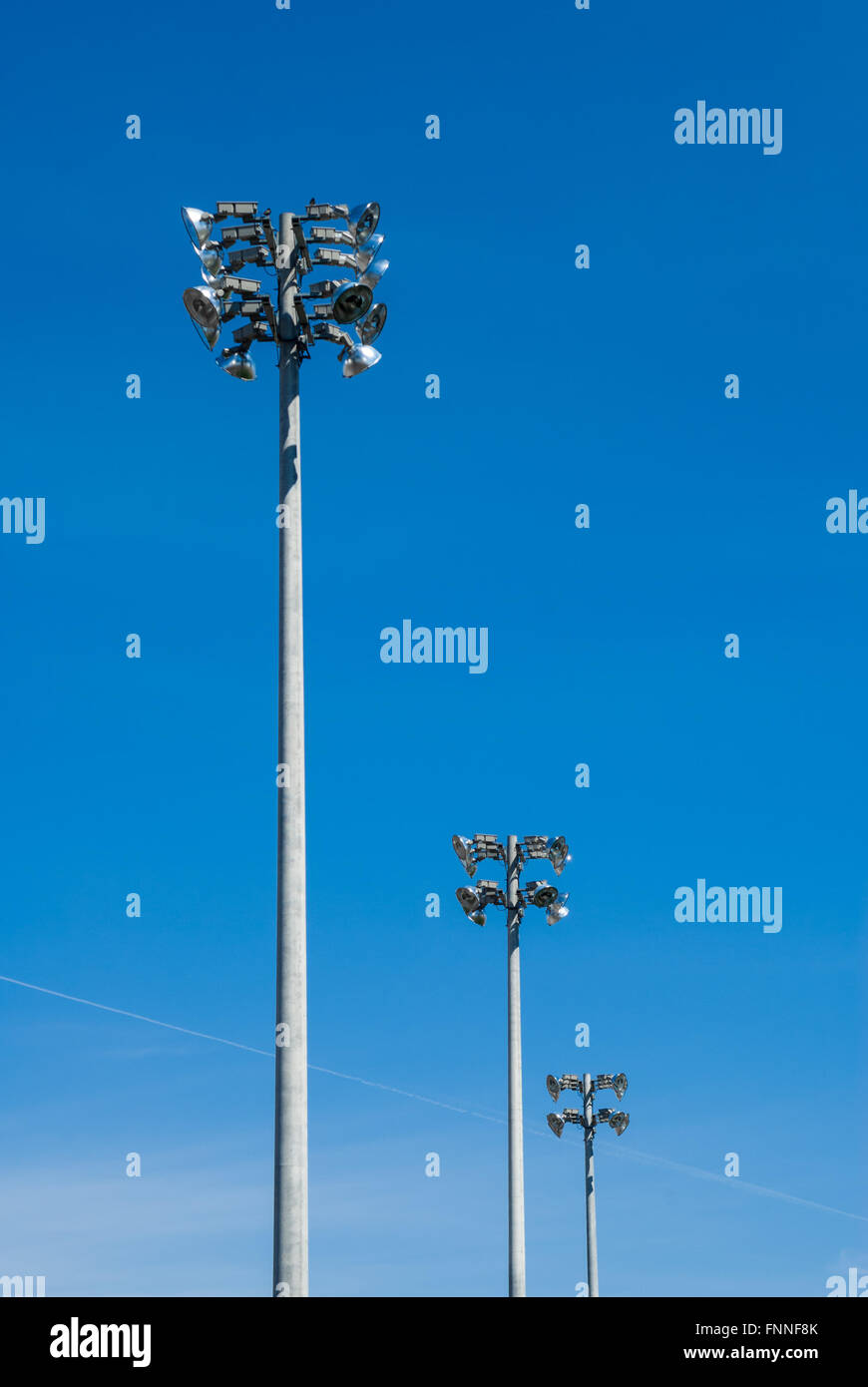 Reihe von drei industriellen Stadion Arbeitsscheinwerfer Türmen auf klaren blauen Himmel. Stockfoto