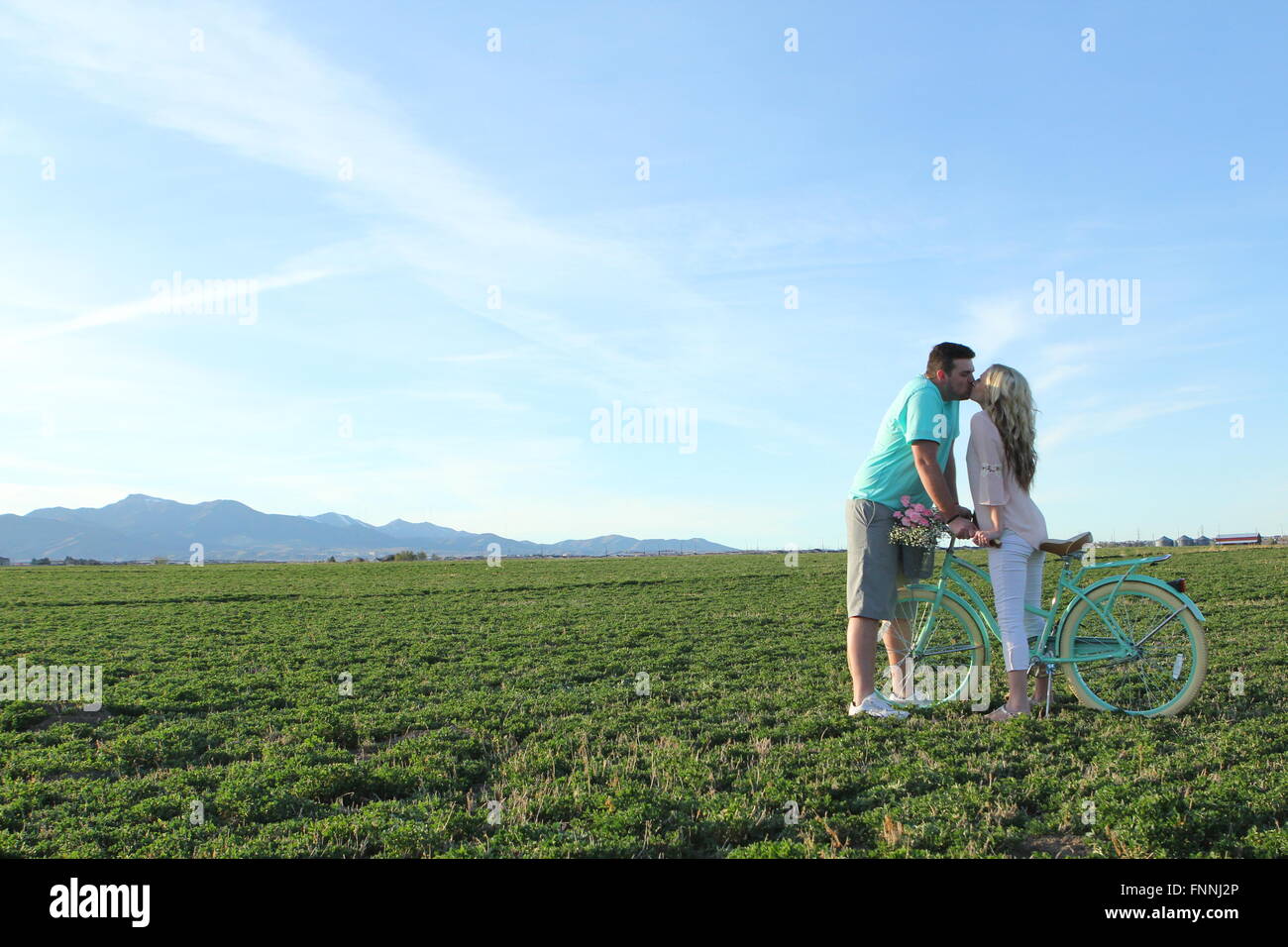 Paar in einem Feld mit einem Fahrrad küssen Stockfoto