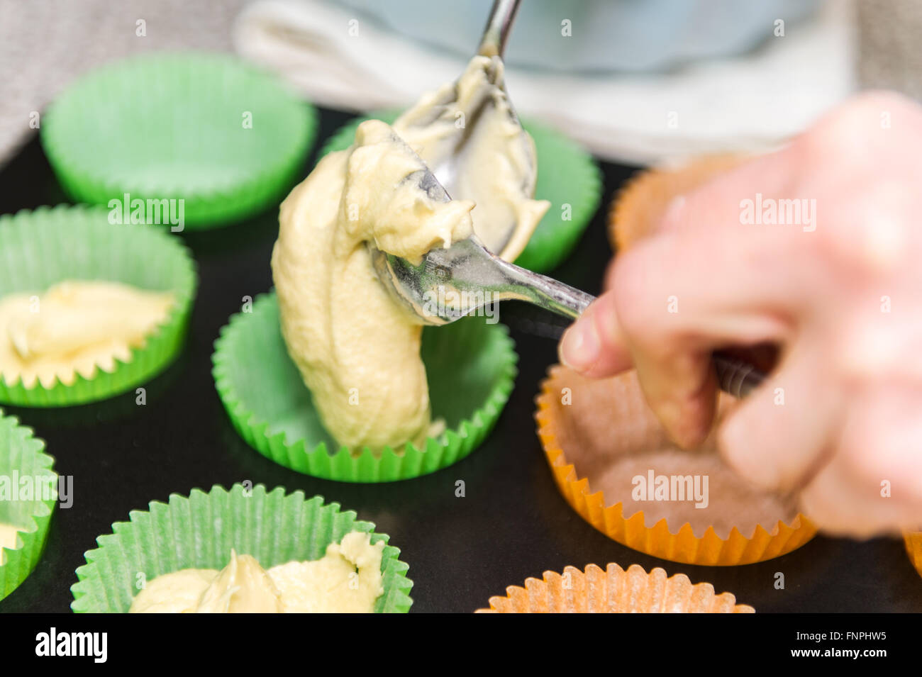 Eine Frau legt Tasse Kuchen Mischung in einer Tasse Kuchen-Fall in eine Küche zu Hause. Stockfoto