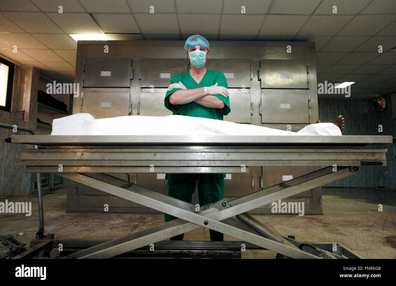 Ein Pathologe steht über einer Leiche in einer Leichenhalle. Stockfoto