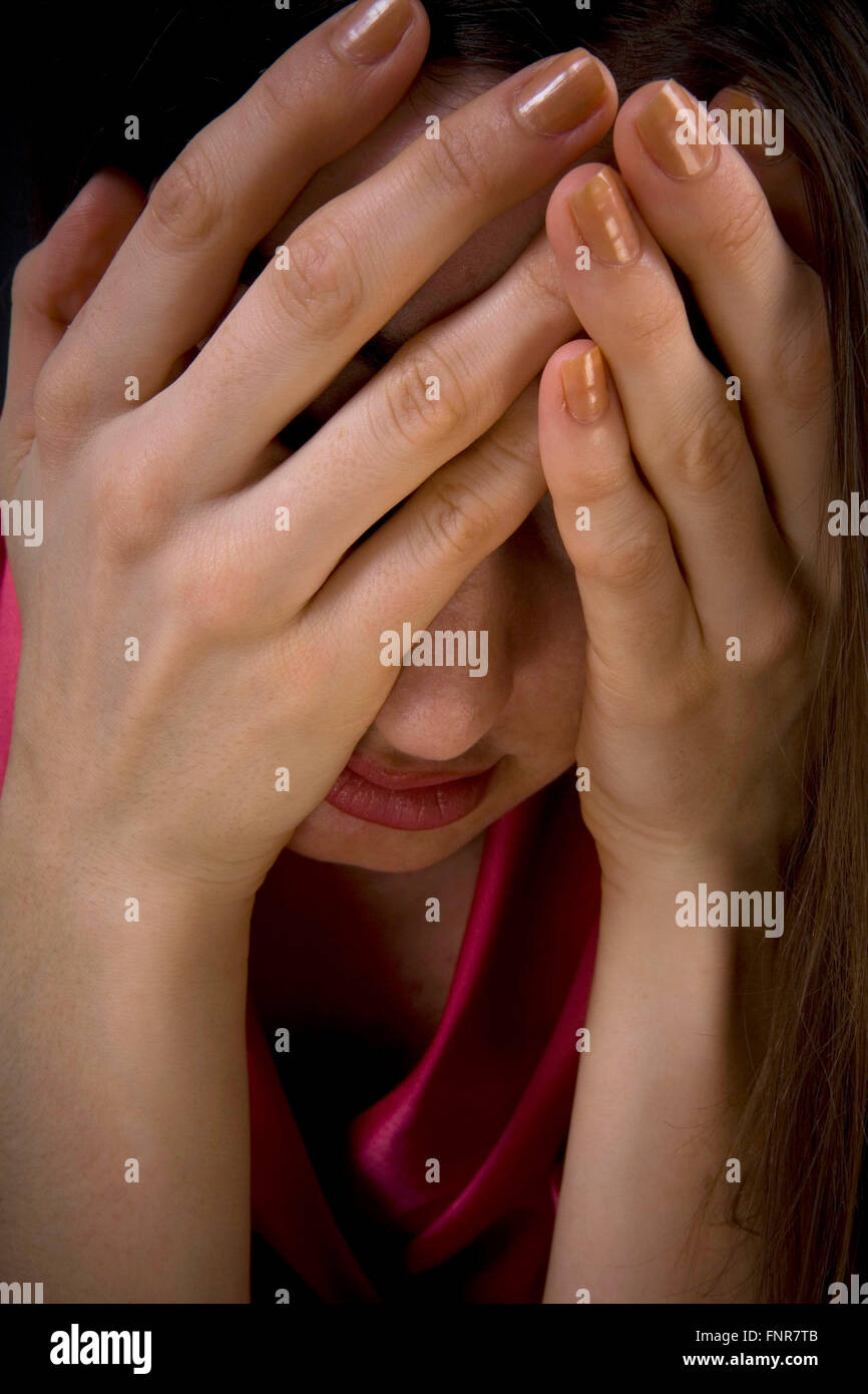 Eine depressive Frau hält ihren Kopf in ihre Hände. Stockfoto
