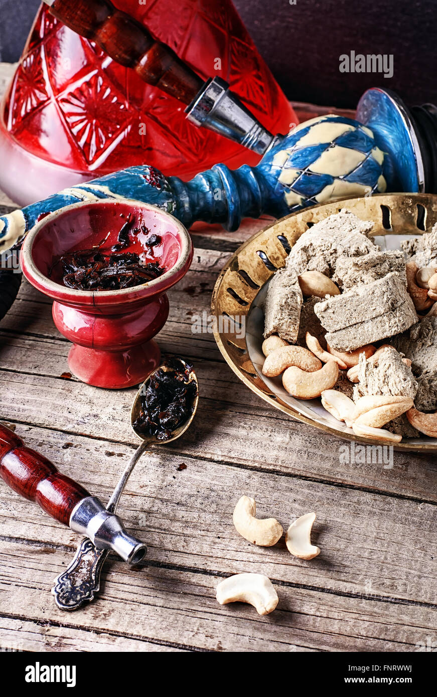 Komposition mit Rauchen Wasserpfeife, Tabak und einen Teller mit Halva und Cashew-Kerne Stockfoto