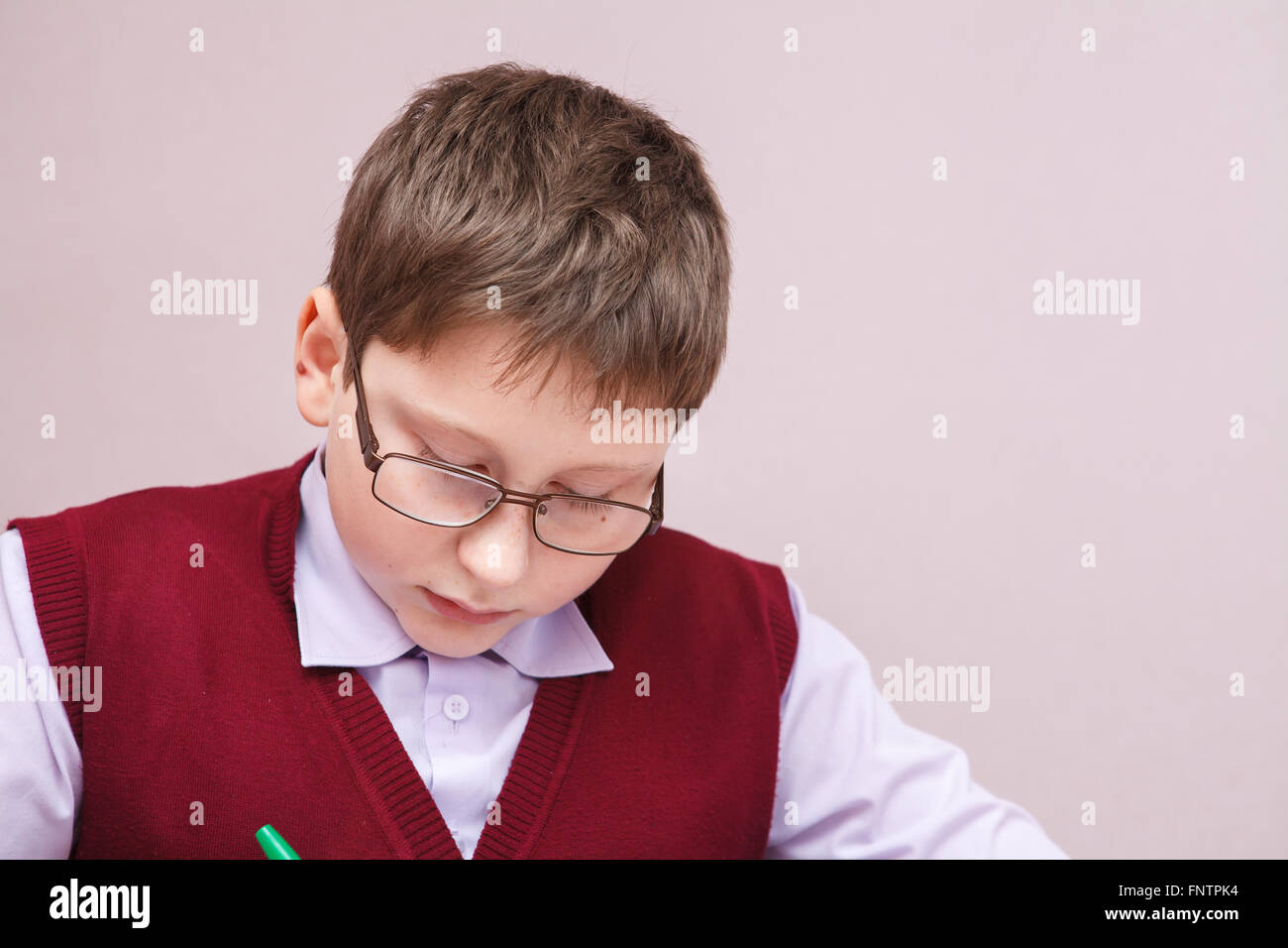 Junge mit Brille sitzt an einem Schreibtisch schreiben Stockfoto