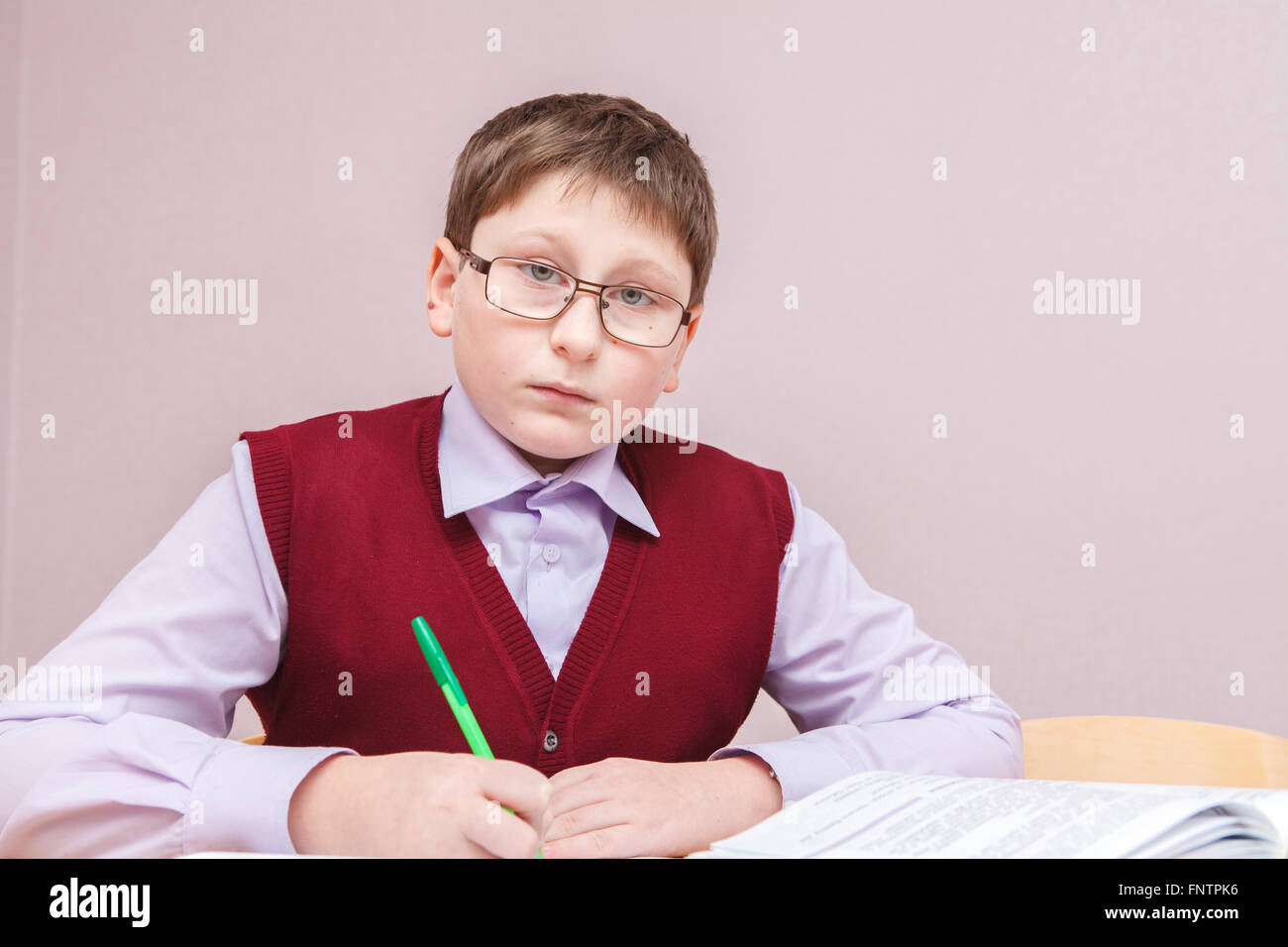 Junge mit Brille sitzt an einem Schreibtisch schreiben Stockfoto