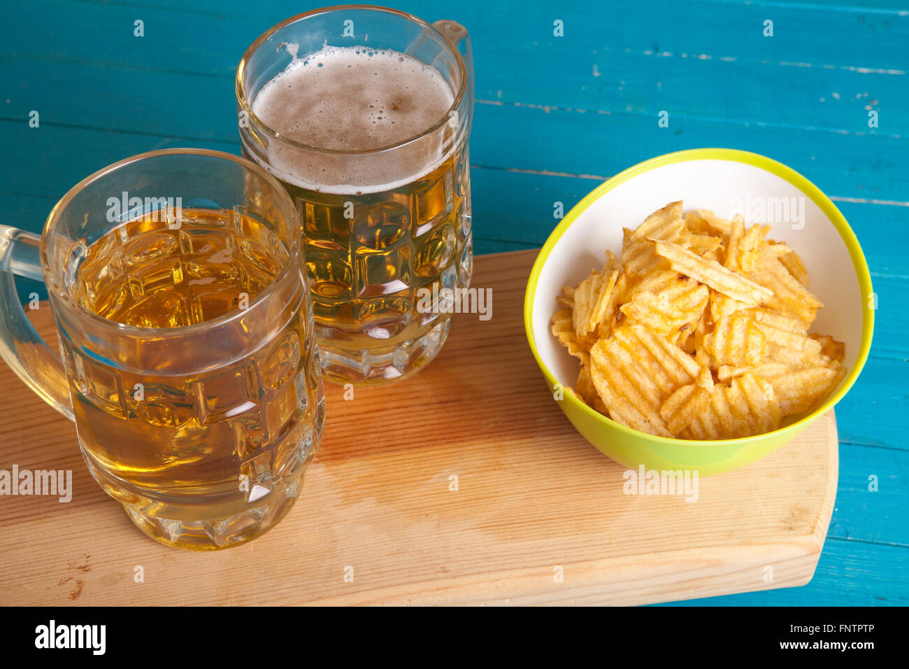 Kartoffel-Chips und zwei Becher Bier auf dem Tisch Stockfoto