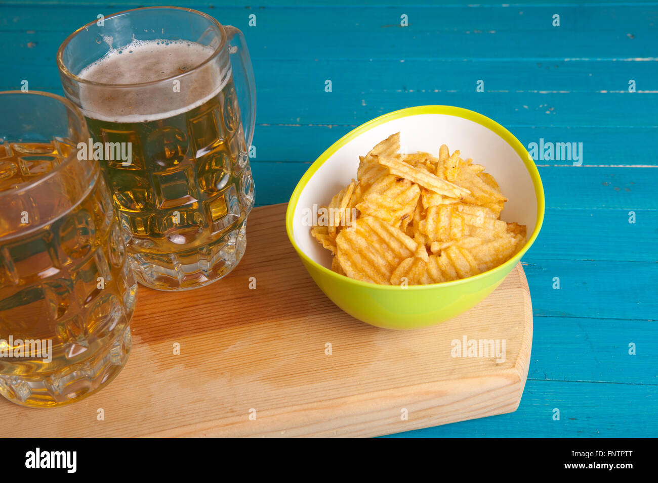 Kartoffel-Chips und zwei Becher Bier auf dem Tisch Stockfoto
