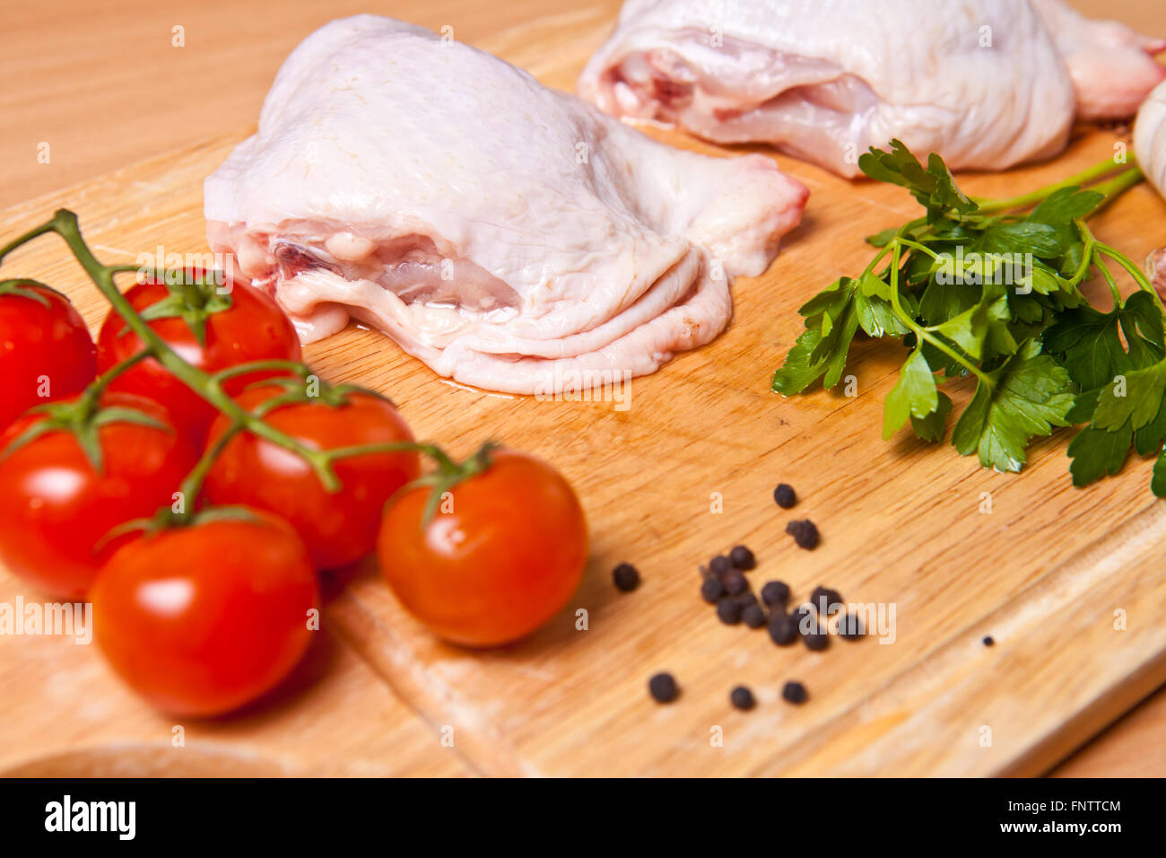 Rohe Hähnchenschenkel mit Gemüse und Gewürzen auf ein Schneidebrett Stockfoto