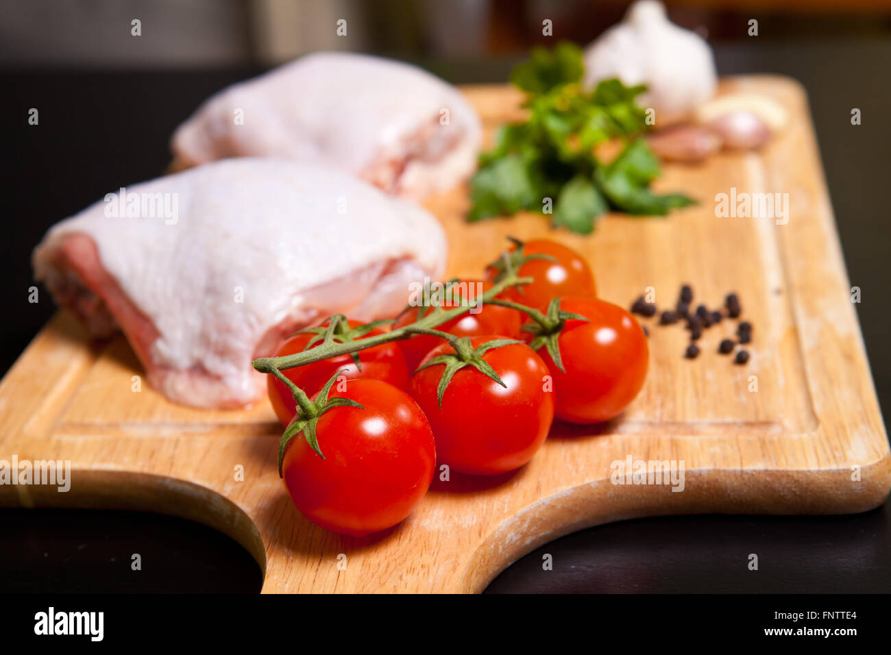 Rohe Hähnchenschenkel mit Gemüse und Gewürzen auf ein Schneidebrett Stockfoto