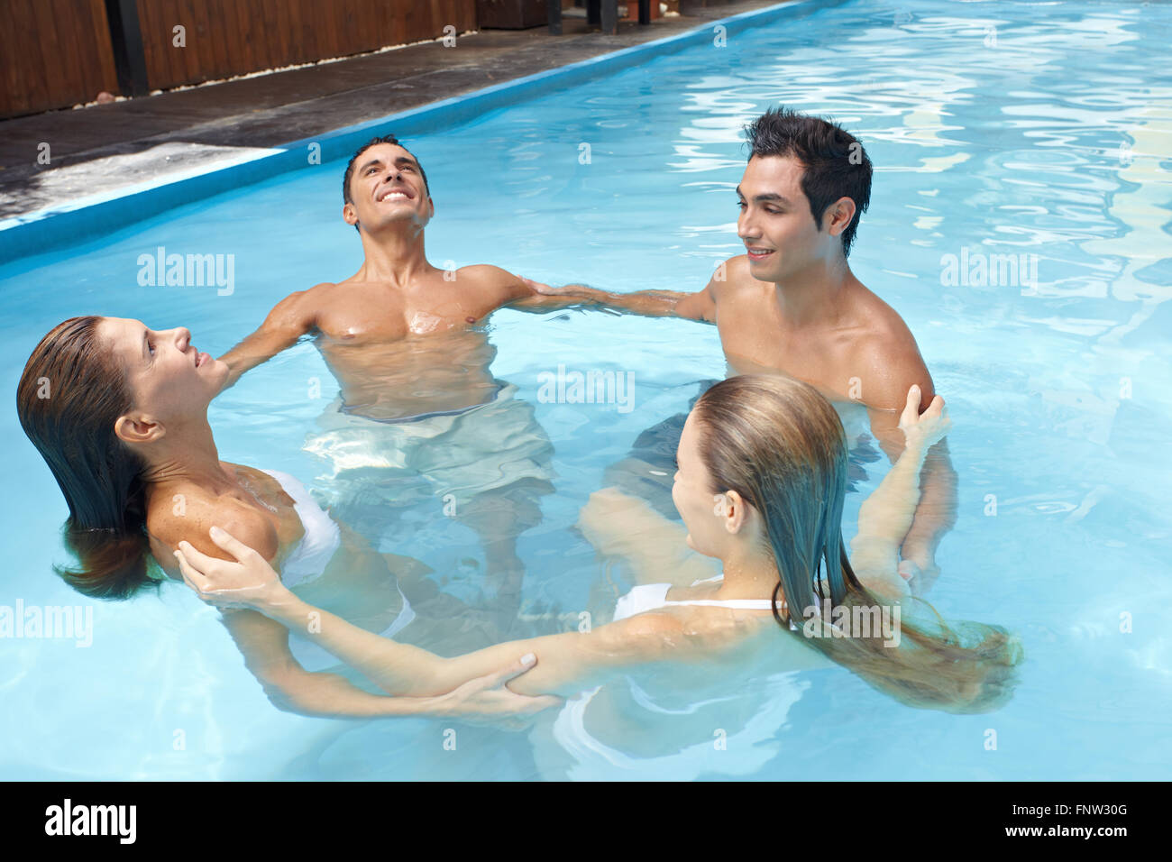 Gruppe mit vier Personen bilden einen Kreis an Aqua-Fitness im Schwimmbad Stockfoto