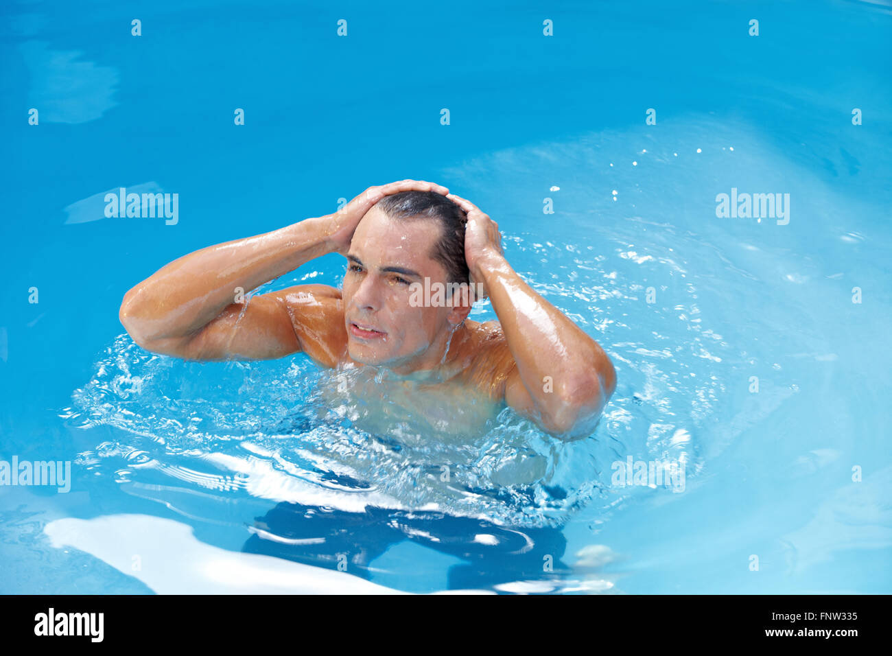 Attraktive junge Mann im Schwimmbad Benetzung seine Haare Stockfoto